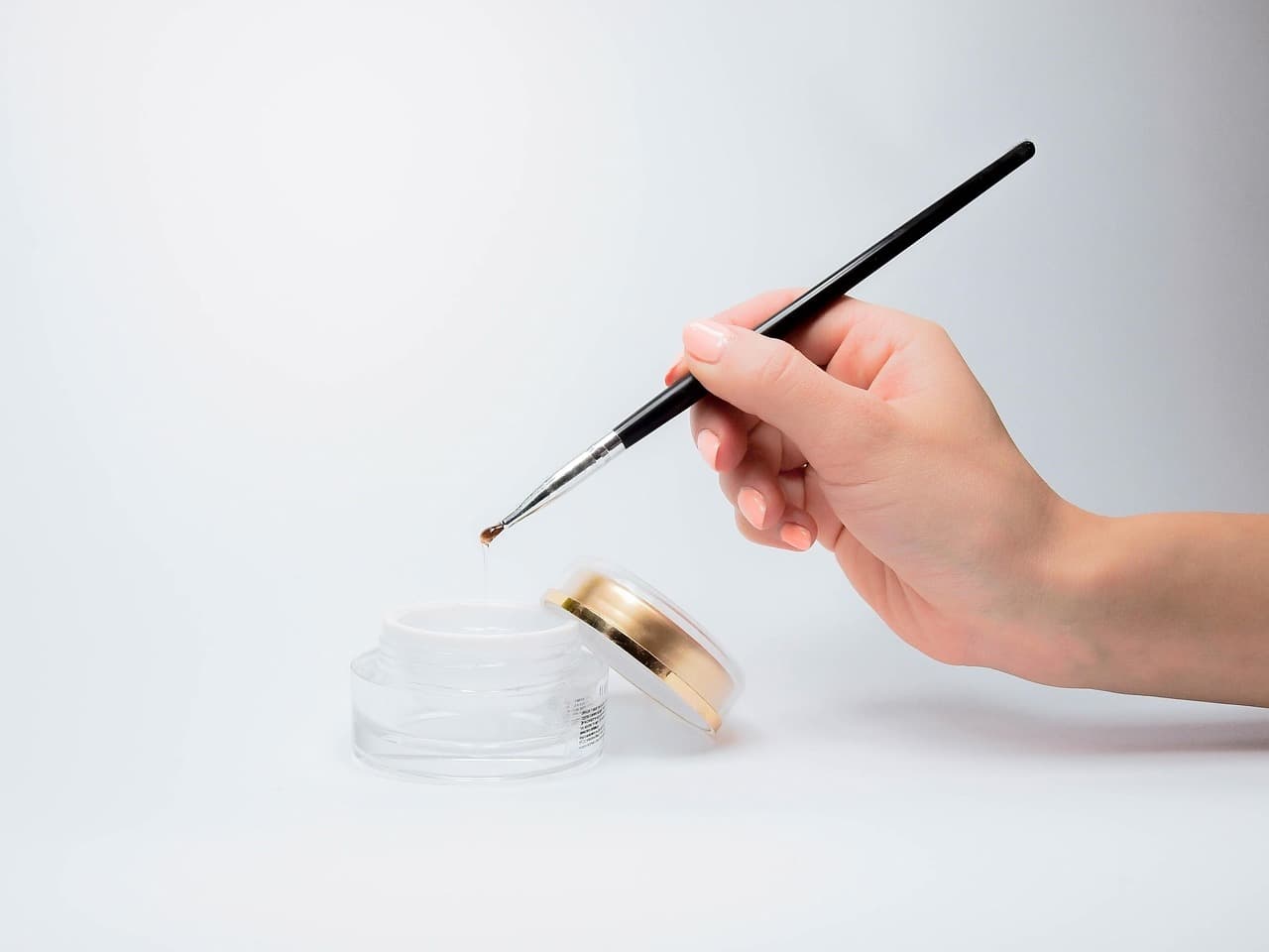 A fine nail art brush and a pot of gel