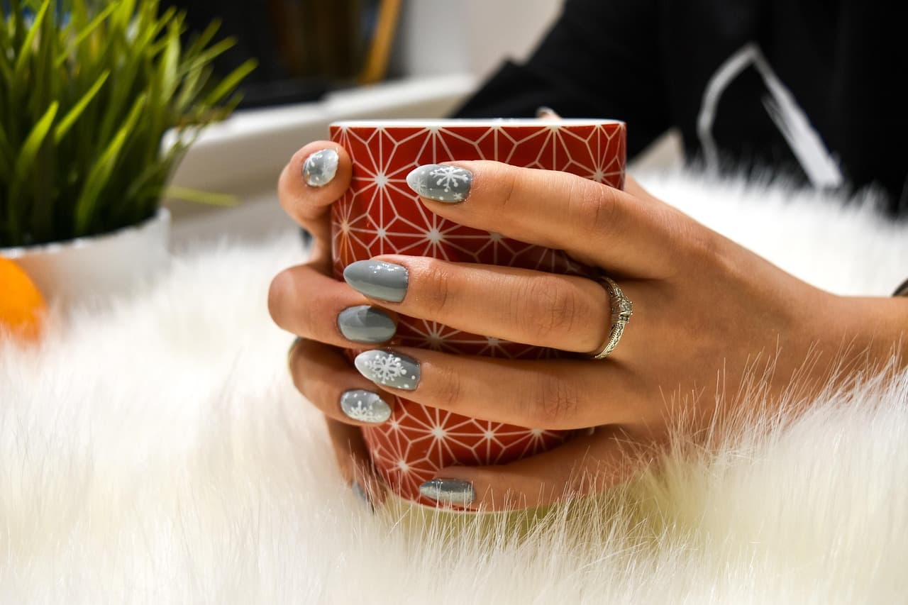 Silver nail art on a hand holding a mug